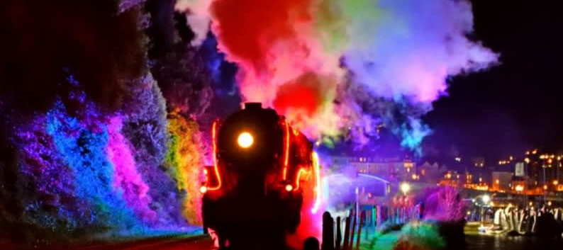 Steam train with rainbow colours reflected in the steam for Christmas